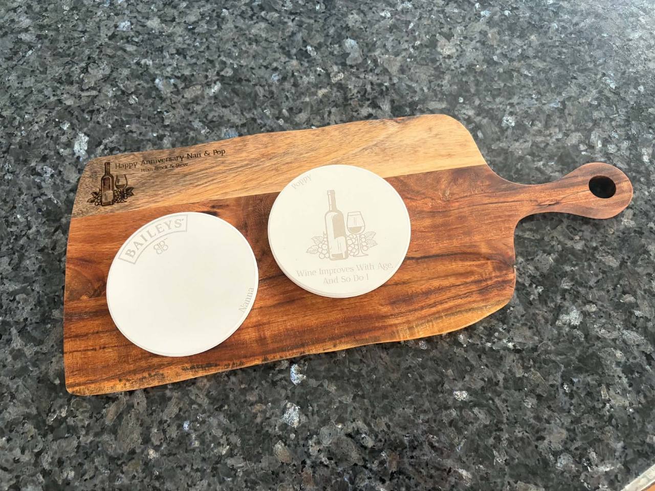 Custom engraved ceramic drink coasters displayed on a wooden cheese board